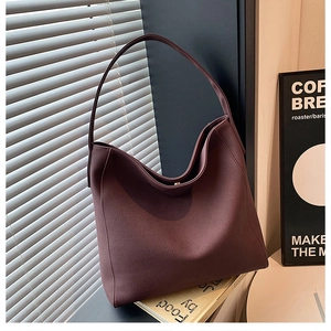Minimalist burgundy large tote bag in matte leather on a desk with a window background