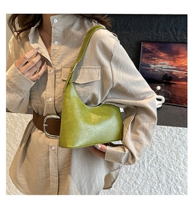 Close-up of minimalist grass green crescent shoulder bag in textured synthetic leather
