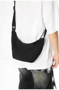 Detail of black nylon crescent crossbody bag featuring adjustable strap and buckle closure