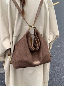 Vintage brown matte suede shoulder bag with gold hardware shown in a lifestyle street shot