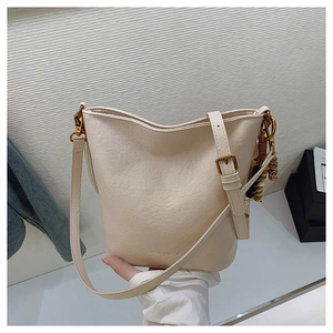 Détail du sac seau crème montrant le logo MUJU & BAGS et le charme en perles boho