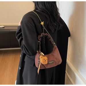 Brown suede crescent bag with scrunchie handle and gold chain detail on model