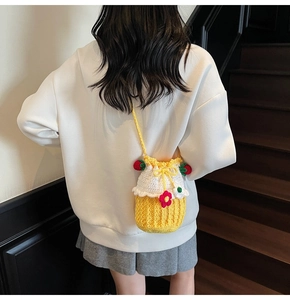 Close-up of handmade crochet cupcake bucket bag with strawberry charms on model