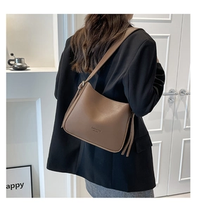 Mocha brown leather shoulder bag with side tassel detail shown on model in studio