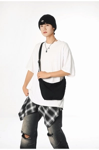 Detail shot of a minimalist black crescent crossbody bag worn by a model on white background