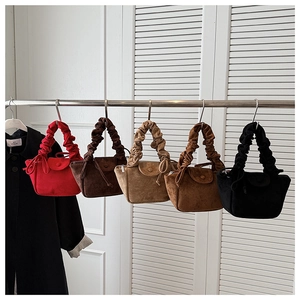 Detailed display of pleated faux suede handbags in five colors hanging on a metal rack