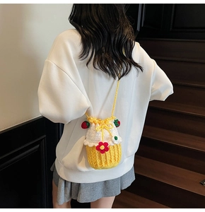 Detail of handmade knit bucket bag with 3D strawberries and floral patterns on white texture