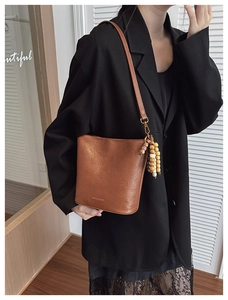 Détail d'un sac seau vintage en cuir marron avec breloque en perles de bois ethniques