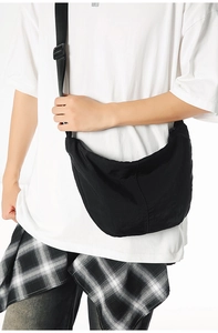Close-up of black crossbody crescent bag with adjustable wide strap on male model