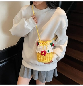 Detail of handmade yellow strawberry knit bucket bag with 3D floral accents on model