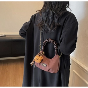 Detail of dark brown suede crescent bag with pleated handle and removable gold chain strap