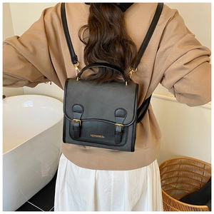 Retro black leather backpack with gold buckles and dual straps shown on a model's back