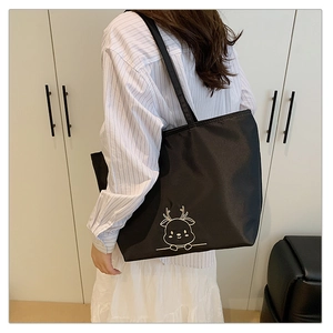 Detail of black nylon tote bag with white cartoon deer print worn on the shoulder