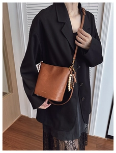 Sac seau marron avec détail de pompon en bois ethnique et fine bandoulière en cuir