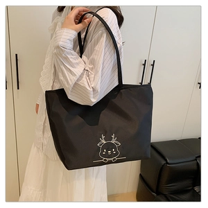 Detail of black tote bag featuring a minimalist white embroidered cartoon reindeer design