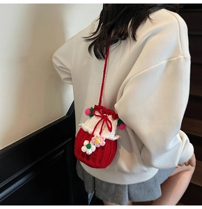 Detailed view of a handmade red and white knit bucket bag with floral crochet charms