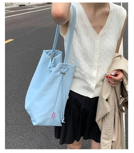 Détail du sac cabas en tissu bleu clair avec étiquette rose Fashion et cordon de serrage
