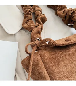 Detail of brown faux suede bucket bag with scrunchie handle and bow tie decoration