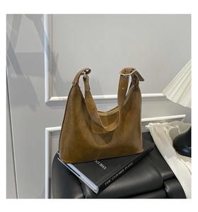 Detail view of brown vintage leather hobo bag with gold hardware on a dark pedestal