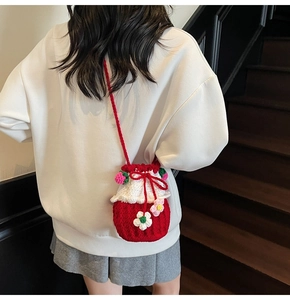 Handmade crochet bucket bag with red and white floral design worn by a model