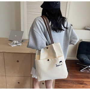 Detailed view of the embroidered canvas tote bag with brown straps and spacious interior