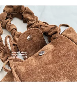 Detail view of the brown suede bucket bag featuring a secure magnetic snap closure