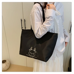 Detail of black canvas tote bag featuring a golden cartoon deer embroidery