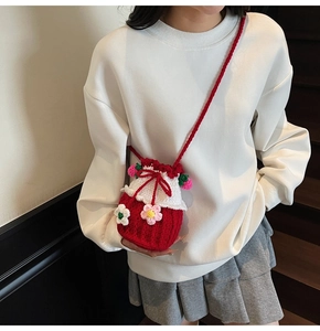 Detail of handmade knit bucket bag with red-white weave and 3D floral accents