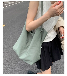 Détail d'un sac cabas en nylon vert clair avec fermeture à cordon porté à l'épaule