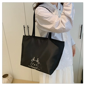 Close-up of elegant cartoon deer embroidery on black canvas tote bag for daily commute
