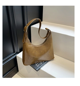 Detail view of vintage brown moon-shaped bag with adjustable strap on minimalist steps