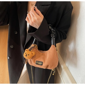 Brown suede crescent bag detail with ruched black handle and cute plush bear charm