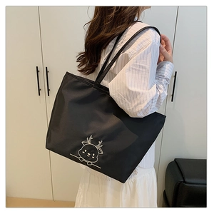 Detail of black canvas tote bag featuring white deer embroidery and long shoulder straps