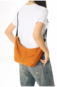 Bright orange nylon crescent crossbody bag worn by model against white background