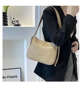 Detail of minimalist cream leather hobo bag with adjustable strap and fashion lettering