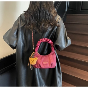 Detail of burgundy pleat handbag with scrunchie handle and removable gold chain strap