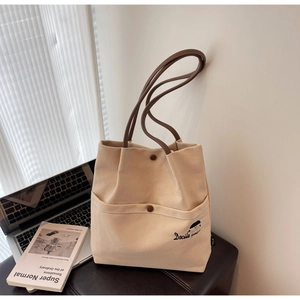 Detail of beige canvas tote with brown handles and elegant girl embroidery