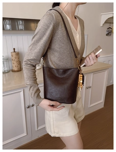 Détail du sac seau vintage marron foncé avec pompon en perles de bois et cuir texturé
