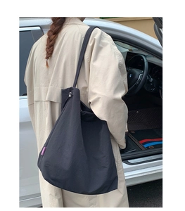 Vue détaillée d'un grand sac cabas en nylon noir avec une coupe décontractée sur l'épaule