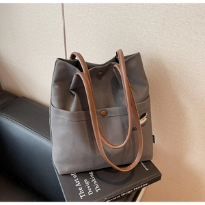 Detail view of grey canvas tote bag with brown handles and cartoon character embroidery