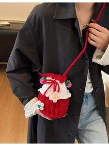 Handmade red crochet bucket bag with knit flowers worn by model in a stylish setting