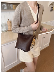 Détail d'un sac seau vintage marron foncé avec charm en perles de bois et bandoulière en cuir