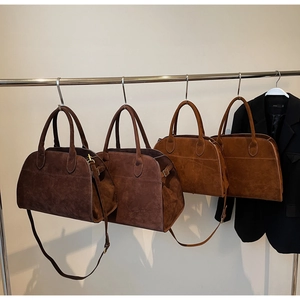 Détail du sac Boston en daim doux avec doubles poignées et bandoulière réglable assortie