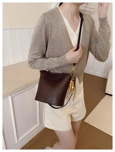 Détail du sac seau vintage en cuir marron chocolat avec bandoulière réglable et gland perlé