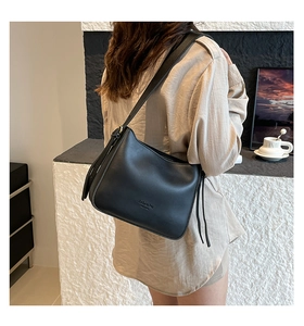 Detail view of black matte leather shoulder bag featuring tassel accents and stylish embossing