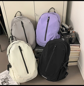 Nylon travel backpacks in grey, purple, beige, and black colors stacked in a retro setting