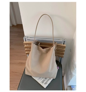 Vue détaillée du grand sac cabas beige sur une chaise avec texture en cuir souple