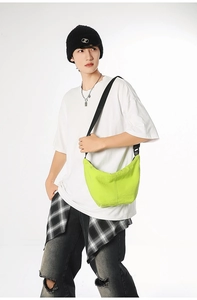 Detail of neon green crescent crossbody bag showing nylon material and adjustable strap