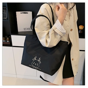 Detail of black canvas tote bag featuring a white cartoon deer print and spacious interior