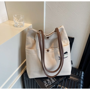 Detail of beige canvas tote bag with Dice Girl embroidery and leather shoulder straps
